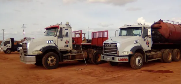Dos chutos Mack, uno con cisterna, en un patio de tierra
