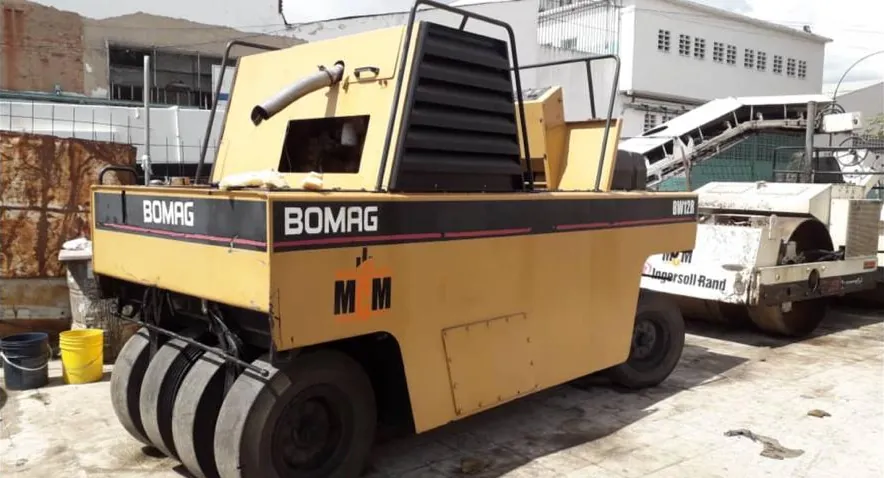 Compactador de neumáticos Bomag con el logo de MCM; detrás, un rodillo Ingersoll-Rand